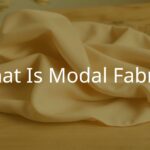 Soft, silky modal fabric draped elegantly on a wooden surface, showcasing its smooth texture and natural sheen, with a beech tree faintly visible in the background, muted earthy tones, realistic.